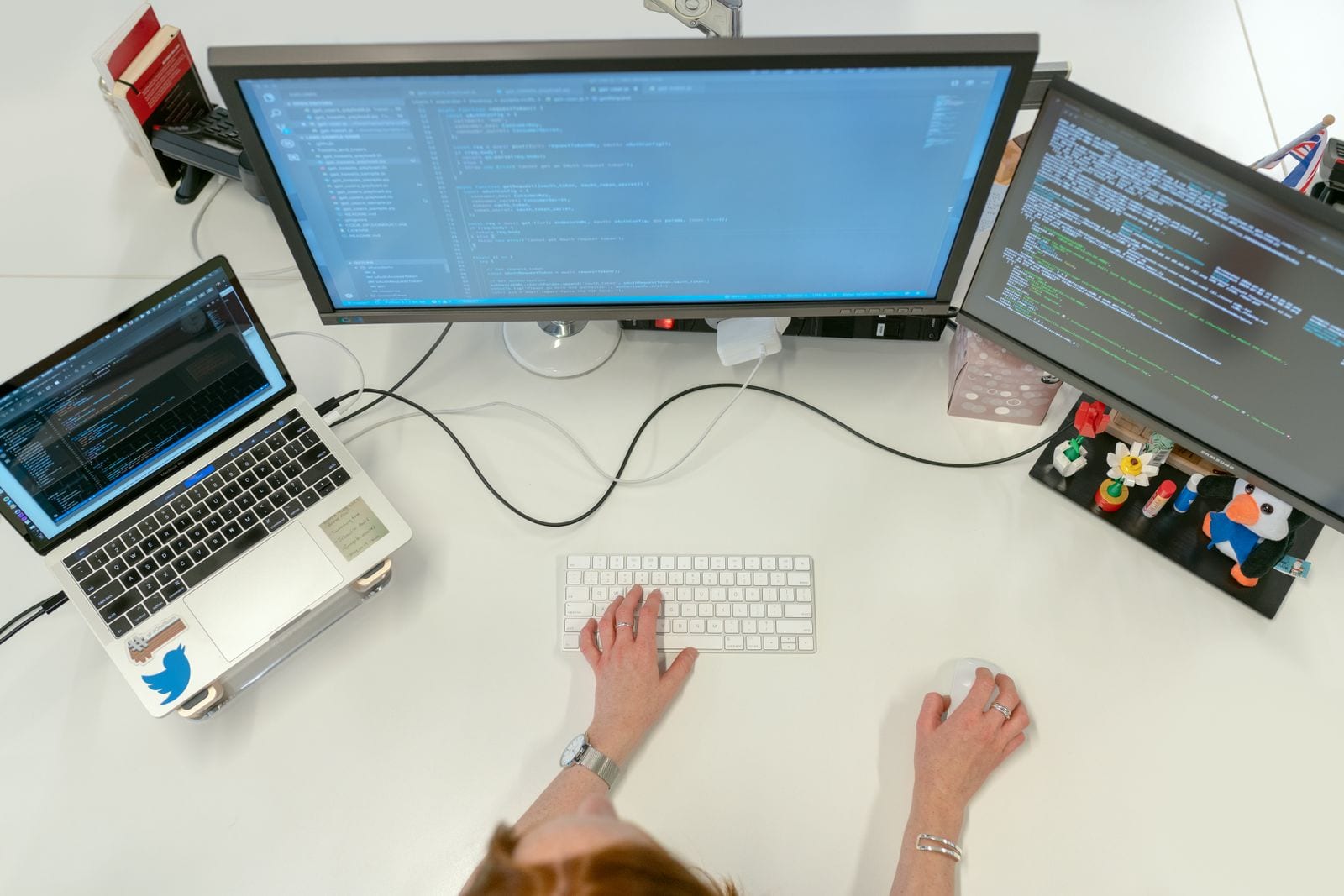 Two colleagues reviewing work together on a laptop at a desk in a bright open-plan office.