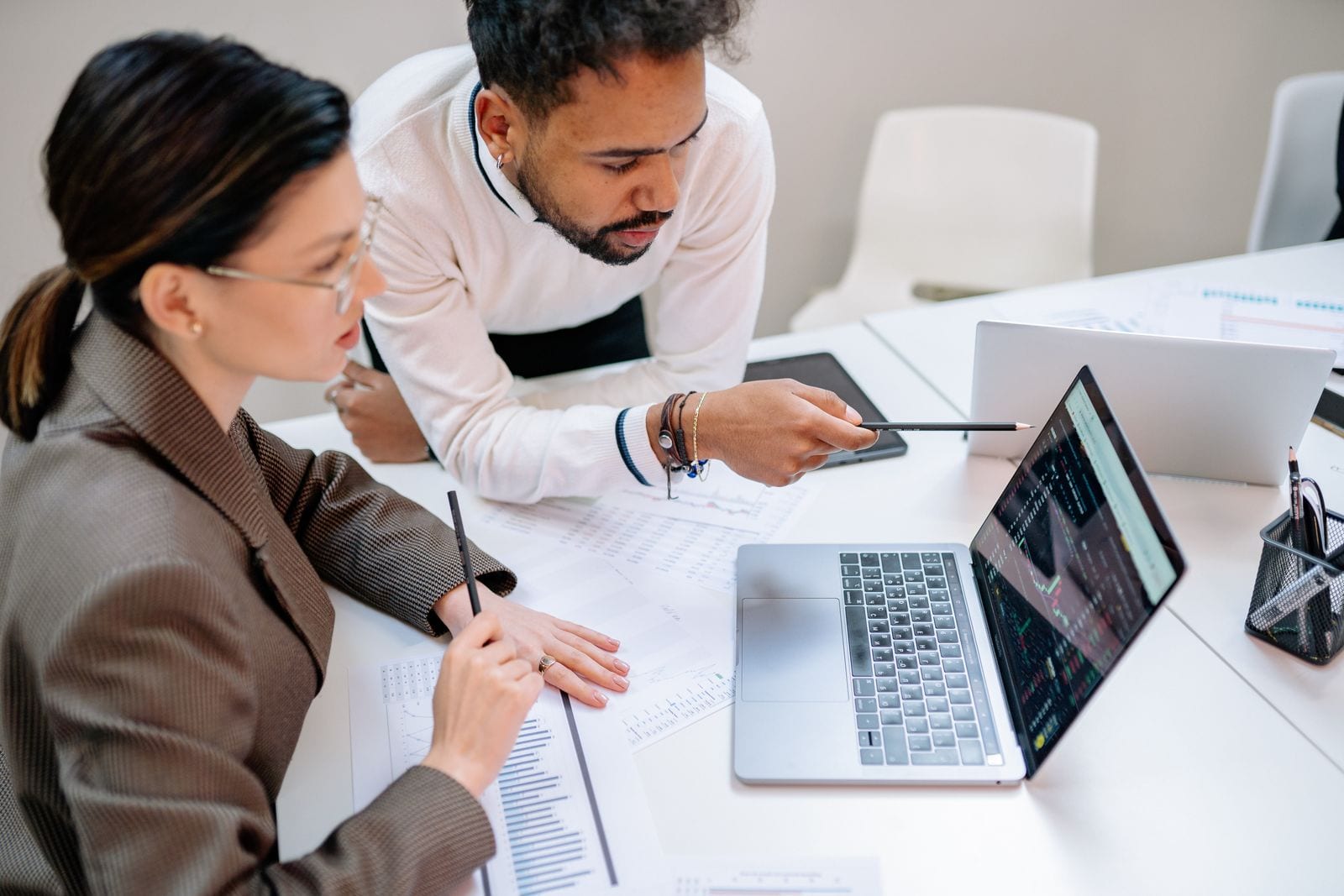 A analytics professional reviewing dashboard data on a laptop in a bright open-plan office.